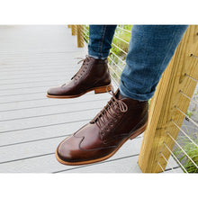 Dark brown leather boot with red hints, natural color sole, brogue design and wingtip